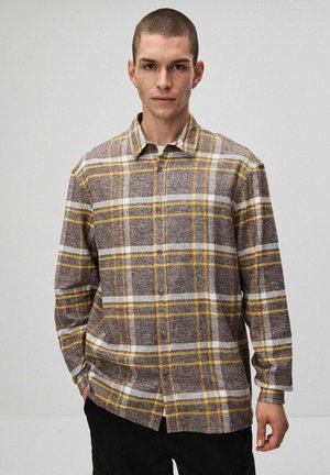 Brązowa i żółta koszula flanelowa w kratę z zapięciem na guziki, kołnierzykiem i długimi rękawami. Miękka tekstura z białymi akcentami w wzorze.