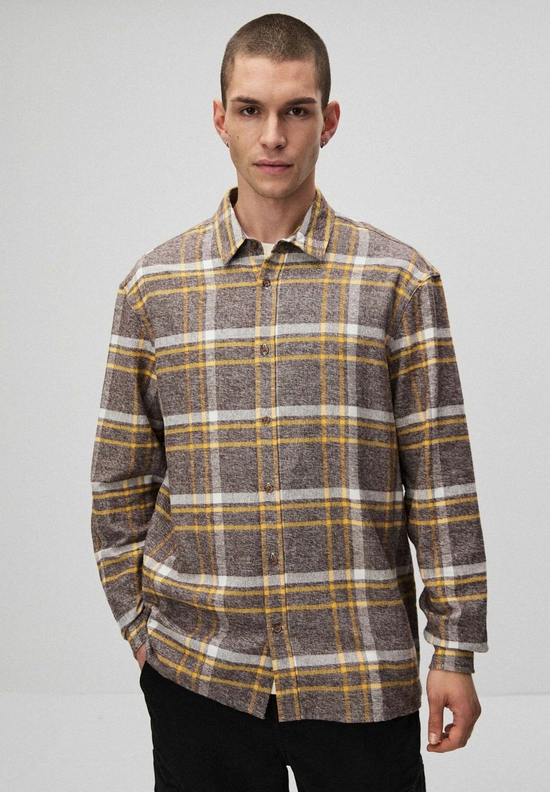 Brązowa i żółta koszula flanelowa w kratę z zapięciem na guziki, kołnierzykiem i długimi rękawami. Miękka tekstura z białymi akcentami w wzorze.