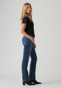 Blue denim jeans with a slim straight fit and subtle back pockets, paired with a solid black short-sleeve t-shirt and black heeled boots.