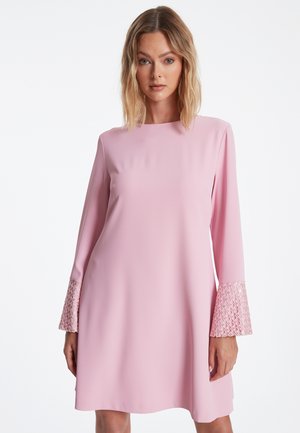 Robe shift rose en tissu lisse, dotée de longues manches cloche avec bord en dentelle. Encolure ronde simple et coupe décontractée.