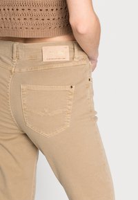 Beige džíny z denimu s fitted designem, opatřené zadní kapsou s dekorativním prošíváním a koženou etiketou na pásku.