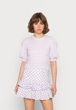 Top cropped de gingham roxo com mangas bufantes, combinado com uma saia branca com um padrão floral lavanda e barra em babados.