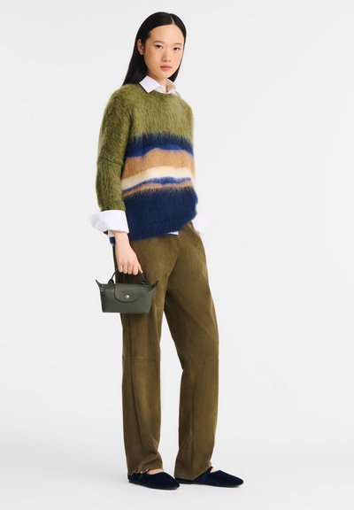 Green fuzzy sweater with blue and tan striped pattern, paired with olive green trousers and navy slippers. Small dark green handbag held.