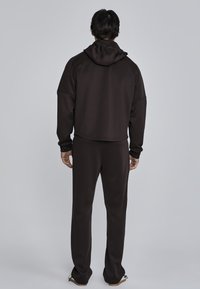 Brown hoodie and matching sweatpants, featuring a relaxed fit, soft material, and a hood. Minimal design with no visible patterns or accents.