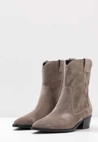 Suède enkellaarsjes in lichtgrijs met een puntige neus en een blokhak. Voorzien van trekbandjes en minimale stiksels voor een strakke uitstraling.