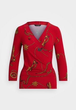 Red wrap top featuring a golden chain and medallion pattern, long sleeves, and a V-neckline. Made from smooth, stretchy fabric.