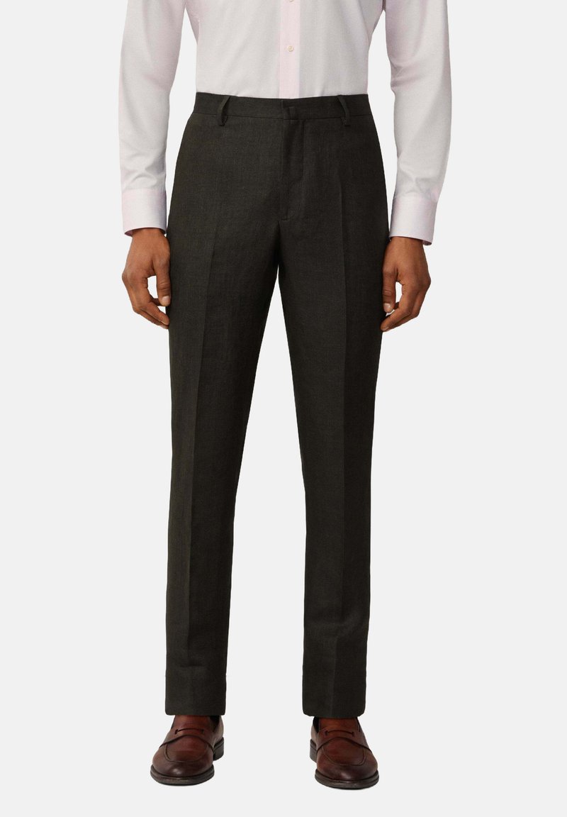 Pantaloni su misura grigio scuro realizzati in un tessuto dalla trama liscia, con una vestibilità dritta e una piega sul davanti. Abbinati a scarpe marroni.