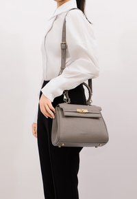 Borsa a tracolla grigia strutturata con superficie texturizzata, accessori in metallo dorato e tracolla staccabile, esposta su uno sfondo neutro.