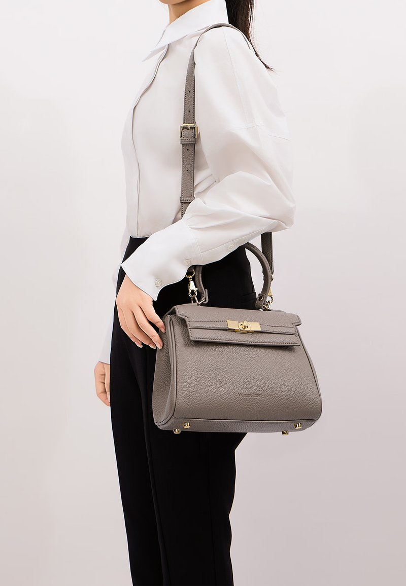 Borsa a tracolla grigia strutturata con superficie texturizzata, accessori in metallo dorato e tracolla staccabile, esposta su uno sfondo neutro.