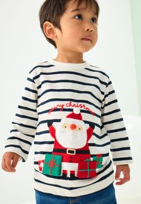 Pikemate triibuline pikkade varrukatega särk kreemikas ja tumesinisena, millel on pehme jõuluvana punases ülikonnas ja jõulukingitustega, brodeeritud tekstiga "Häid jõule".