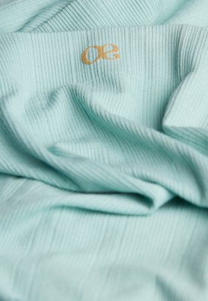Tissu côtelé bleu clair avec une texture douce, arborant un petit logo doré "50". Le matériel semble léger et légèrement froissé.