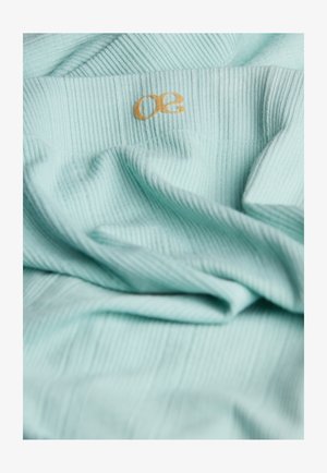 Helles türkisfarbiges, geribbeltes Material mit einer weichen Textur, das ein kleines goldenes "50"-Logo trägt. Das Material wirkt leicht und leicht zerknittert.