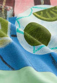 Färgglatt tyg med abstrakta mönster av gröna blad, en mörk oval form och blå texturer, med en slät yta och mjuka veck.