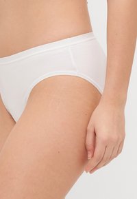 White cotton underwear with a smooth texture, low-rise design, and seamless edges. No visible patterns or hardware.