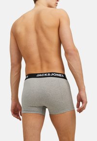 Boxers gris avec une ceinture élastique noire portant le logo "JACK & JONES", offrant un ajustement serré et une texture en coton lisse.