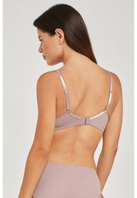 Beha van zacht mauve stof met een gladde textuur, dunne verstelbare bandjes en een haak-en-oogsluiting aan de achterkant. Eenvoudig en minimalistisch ontwerp.