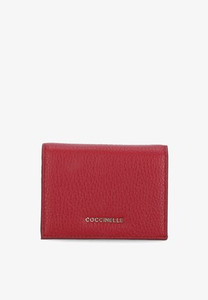 Czerwona skórzana portmonetka o teksturowej powierzchni, złotym logo na dole i kompaktowym prostokątnym kształcie. Prosty i funkcjonalny design.