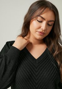 Maglione nero a V con motivo a zigzag testurizzato, polsini a coste e un materiale in maglia morbido con una leggera scintillio.