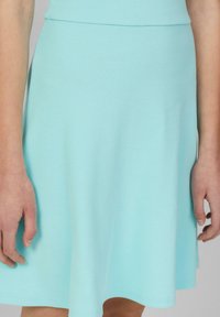 Ein hellblaues, geripptes Strickkleid mit einem taillierten Oberteil und einem ausgestellten Rock, das eine sanfte Textur und eine fließende Silhouette aufweist.