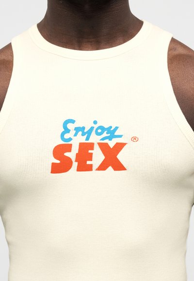 Ελαφρύ κρεμ αμάνικο τοπ με ριμπ υφή και πολύχρωμο γραφικό τύπωμα με τη φράση "Enjoy SEX" σε μπλε και πορτοκαλί.