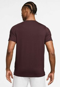 Maroon kratka majica s kratkimi rokavi, izdelana iz mehkega materiala z okroglo izrezom, ki se ponaša z gladko teksturo in minimalnimi šivi.
