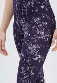 Navy leggings met een multikleurig bloemenpatroon, hoge taille, zachte textuur en een aangesloten ontwerp, met levendige paarse en roze accenten.