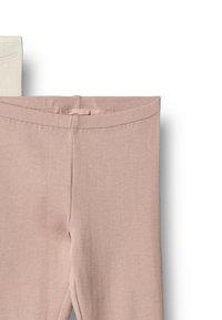 Close-up af beige og lyse cremefarvede ribstrikkede leggings foldet ved taljen mod en hvid baggrund.