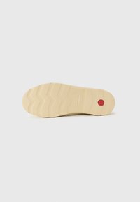 Semelle de chaussure en caoutchouc beige avec un motif en zigzag texturé ; présente un accent circulaire rouge et un marquage sur le côté pour améliorer l'adhérence et la stabilité.