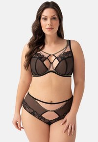 Set di lingerie in rete nera con un reggiseno con dettagli in pizzo, cinture incrociate e un coordinato slip a vita alta con ritagli.