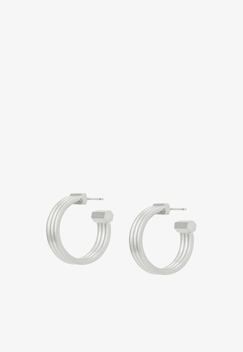 Paire de boucles d'oreilles anneaux en argent avec une texture rainurée et des détails hexagonaux aux extrémités, dotées d'attaches droites pour oreilles percées.