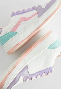 Sneaker mit weißem Lederoberteil, lila und türkisfarbenen Akzenten, pinkem Glitzer-Swoosh und strukturiertem Gummisohle. Verfügt über kontrastierende Pastell-Schnürsenkel.