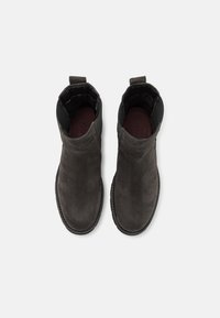 Bottines en suède gris foncé avec une texture lisse, des panneaux latéraux élastiques et une languette à l'arrière. Semelle en caoutchouc noir cousue.