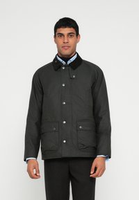 Tmavě zelená, voděodolná bunda s manšestrovým límcem, patentními knoflíky, dvěma předními kapsami a logem na levé kapse. Má raglánové rukávy.