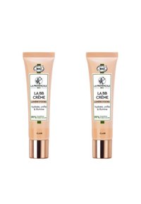 Deux tubes de crème BB avec un emballage beige clair, des accents dorés et des étiquettes blanches. Le texte comprend le nom du produit et des informations sur les ingrédients naturels.