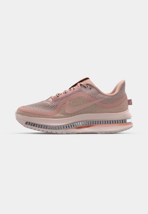 Bežecká obuv Nike v svetloružovej a béžovej sieťovine, s polstrovanou podrážkou, kovovými akcentmi a textúrovaným dizajnom na hornej časti.