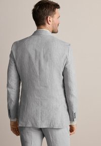 Helles graues Leinen-Sakko mit glatter Textur, schlanker Passform, Reverskragen und geknöpften Ärmelabschlüssen mit kontrastierenden Streifenakzenten.