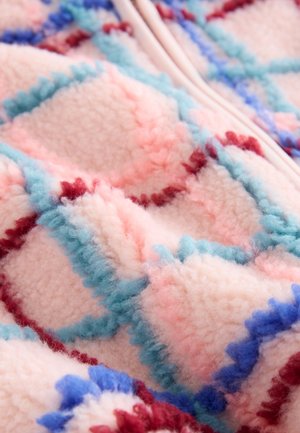 Fleece deken met een roze ondergrond, voorzien van een diamantpatroon in lichtblauw, rood en donkerblauwe accenten; zachte, pluizige textuur.