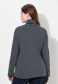 Topp med lång ärm i marinblå och krämrandig design med hög hals. Mjuk tyg, figursydd design, böjd nederkant och sidokilar för större rörelsefrihet.