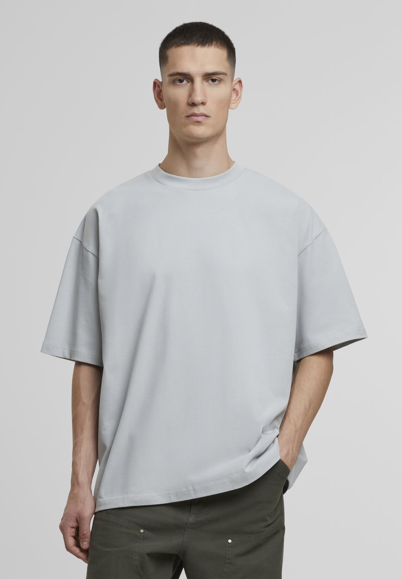 Lys grå oversized kortærmet t-shirt med rund halsudskæring, lavet af glat stof, med drop-skulder og en afslappet pasform.