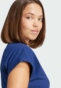 T-shirt blu a maniche corte con una consistenza morbida e un design aderente, dotato di un collo rotondo e dettagli sottili sulle spalle.