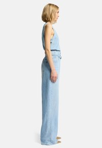 Lichtblauwe denim jumpsuit met mouwloos ontwerp, wijde pijpen en ceintuur in de taille, met een gladde textuur en subtiele stiksels.