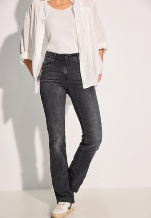 Zwart denim met hoge taille, met een rechte pijp, gecombineerd met een witte tanktop en een licht semi-doorschijnend shirt. Opvallende stiksels.