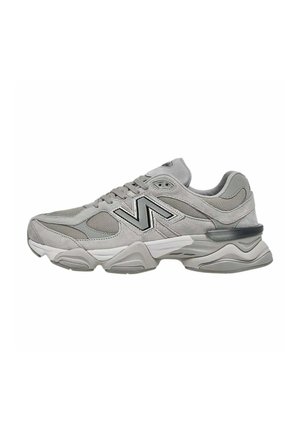Scarpa atletica grigia con una combinazione di materiali in rete e suede, caratterizzata da una spessa suola bianca e un logo nero a contrasto. Design con punta arrotondata.