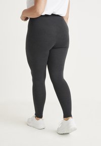 Hoge taille, elastische leggings van donkergrijze stof, met een gladde textuur en een aansluitend ontwerp. Gemaakt om te dragen met witte sportschoenen.