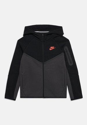 Sort og mørkegrå Nike lynlåstrøje med hætte, forlommer, lynlåslomme på ærmet og orange Nike-logo på brystet.