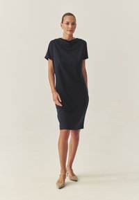 Dunkelblaues Kleid mit einem Schalkragen, kurzen Ärmeln und lockerer Passform, das bis zur Mitte der Waden reicht, gefertigt aus einem glatten Stoff.