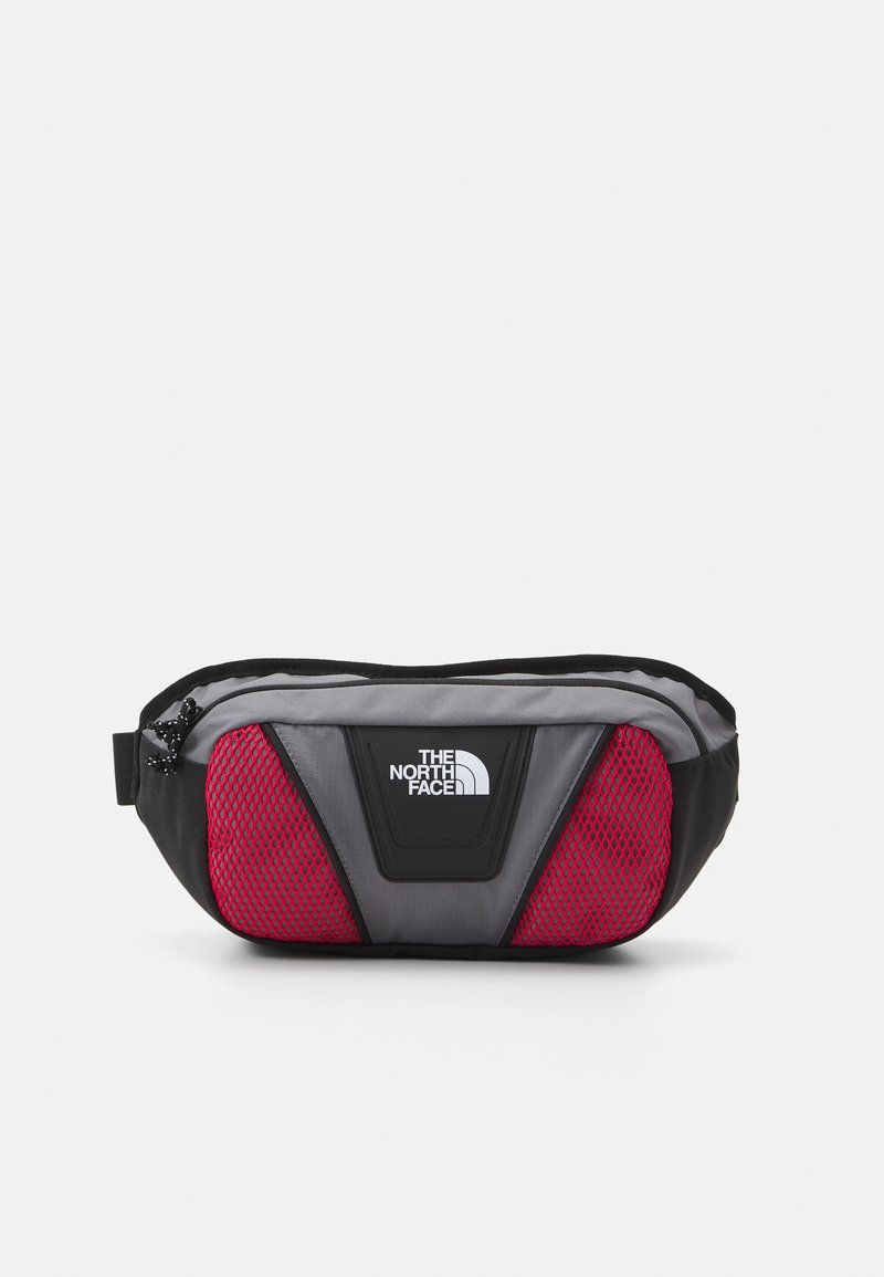 Sac banane gris et noir avec des panneaux latéraux en mesh rouge et un logo blanc The North Face au centre à l'avant.