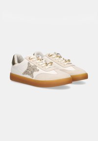 Zapatillas blancas con acentos de ante beige, estrella dorada brillante en el costado, etiqueta dorada en el talón y grandes adornos de gemas transparentes en los cordones crema.