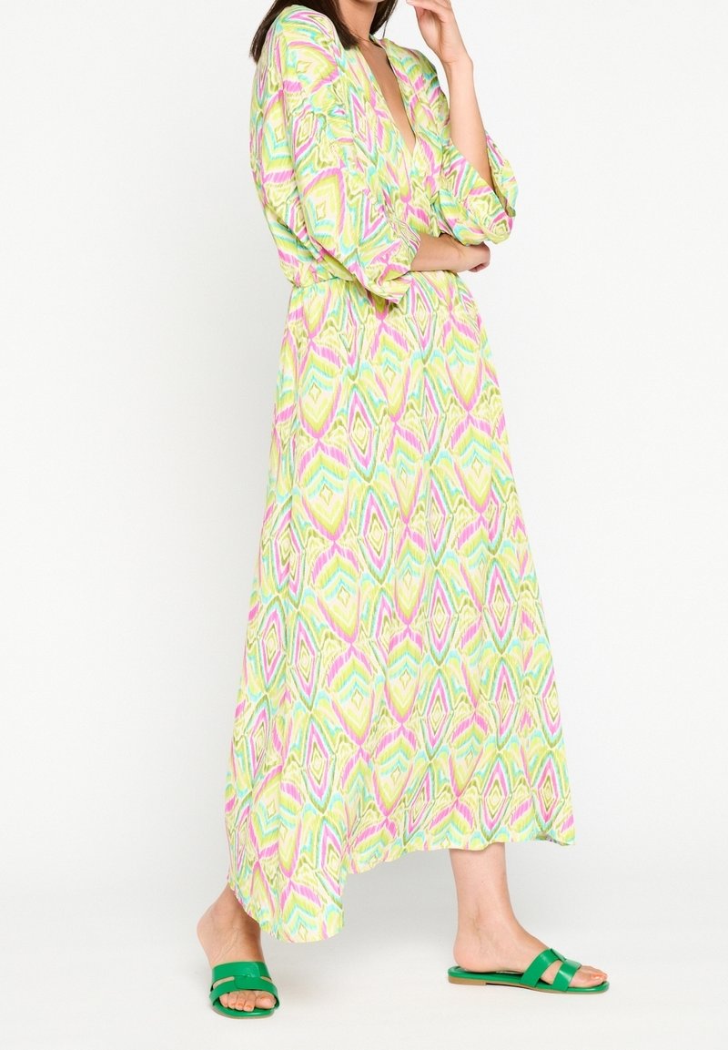 Robe maxi en tissu léger avec un motif géométrique jaune vif, rose et vert. Présente des manches amples et une taille ceinturée.