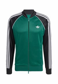 Zeleni i crni zip-up jakna s bijelim trostrukim trakama, rebrastim manžetama i malim logotipom na lijevoj strani prsnog koša. Glatka tekstura.